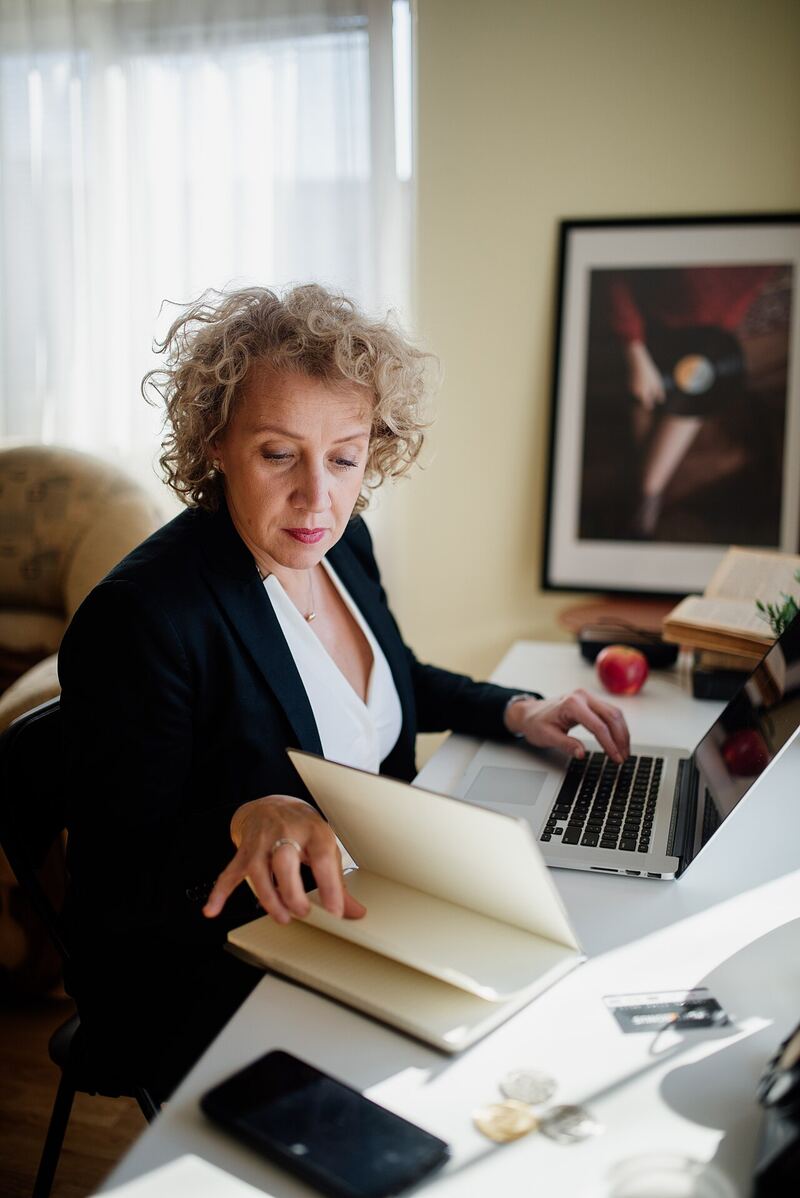 A CAD professional working at a desk with a laptop and documents in a bright office