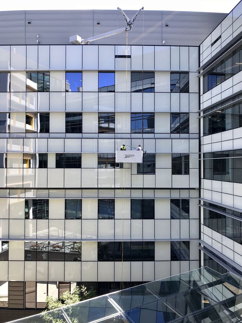 A facilities maintenance worker cleaning a building facade as part of routine property upkeep
