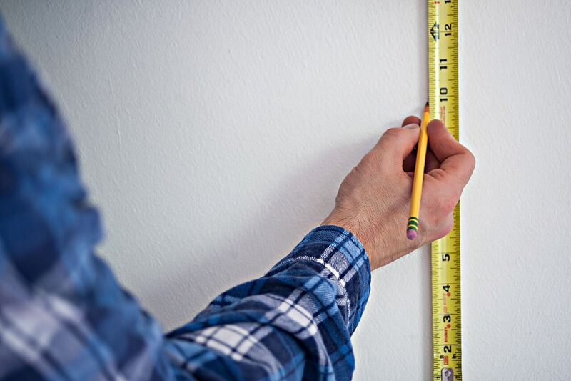 Measuring and marking a wall with a pencil and tape measure for an accurate diagram