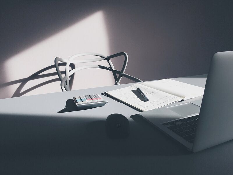 A desk with a laptop and calculator, representing evaluating software licensing costs