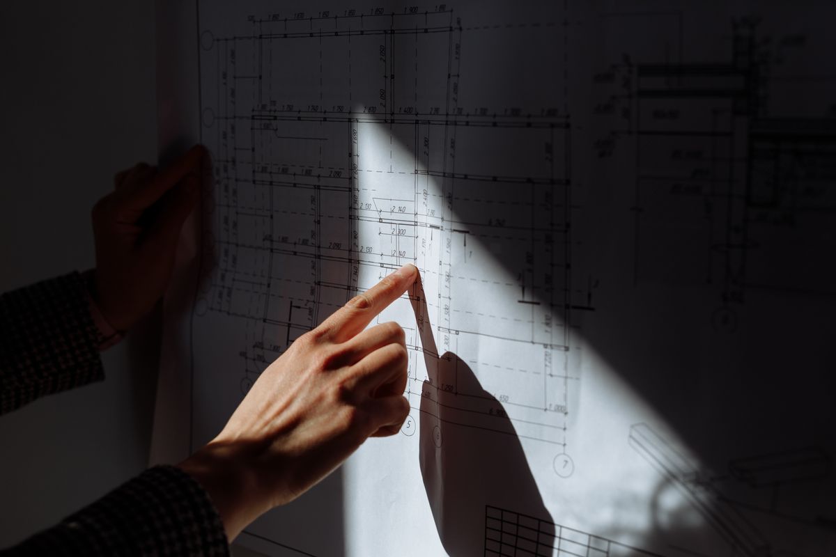 Hand reviewing an architectural blueprint — progeCAD vs AutoCAD drafting comparison