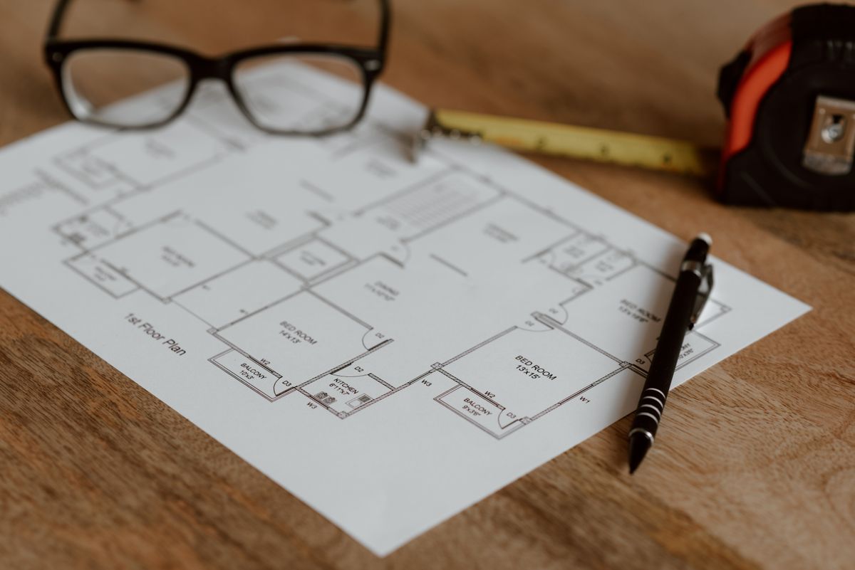 Floor plan drawing with glasses and a tape measure on a desk