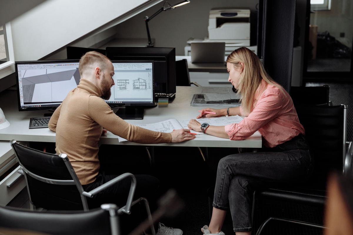 Two colleagues reviewing a CAD drawing together at a desk